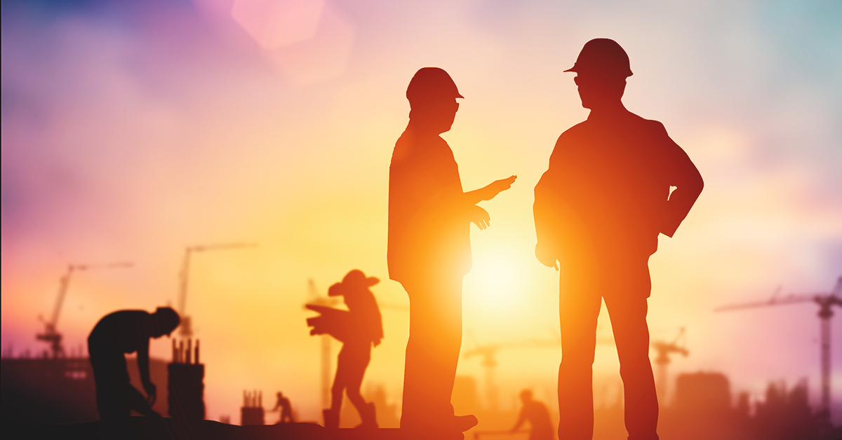 2 workers in a construction setting at sunset