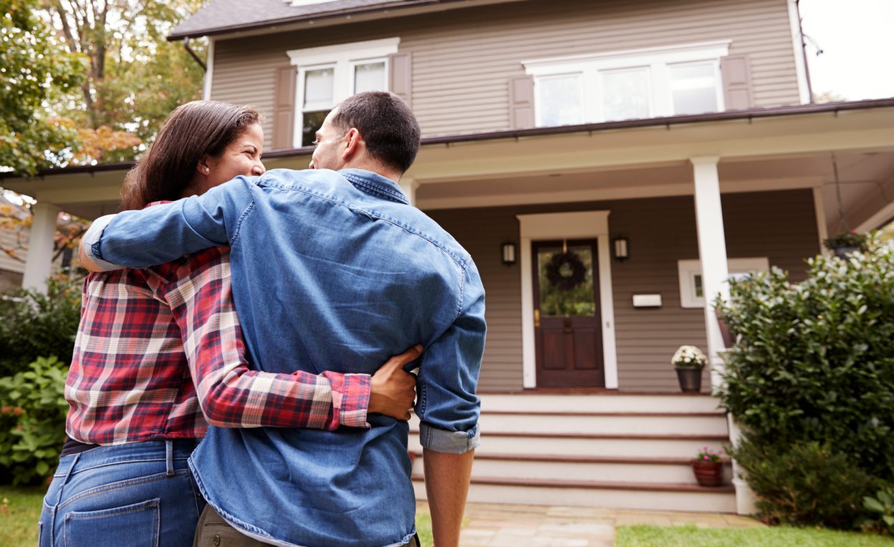 Young couple in front of their first home