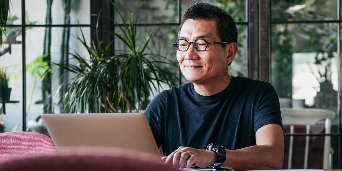 Middle-aged Asian man on his laptop while at his plant shop