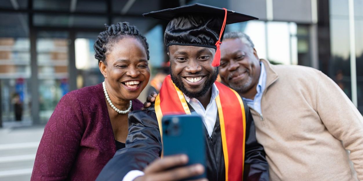 Black family celebrating with college graduate taking a selfie