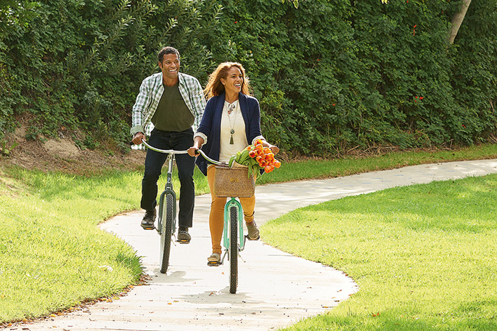 a couple riding bikes through a park