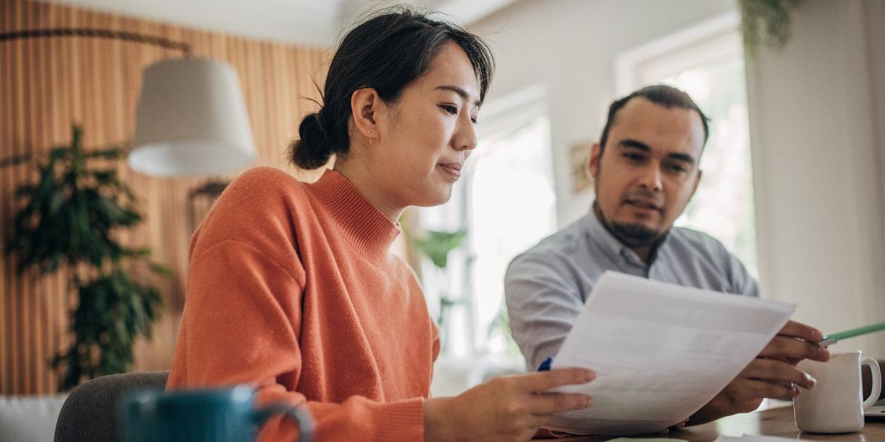 Mixed couple at home looking at investment account statements