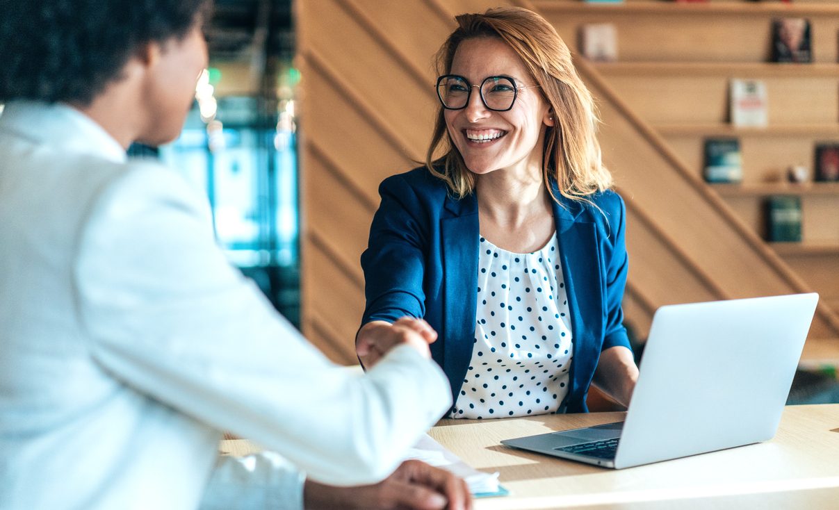 Business people shaking hands in the office. Group of business persons in business meeting. Two entrepreneurs on meeting in board room. Corporate business team on meeting in modern office. Female manager discussing new project with her colleagues. Company owner on a meeting with her employee in her office.