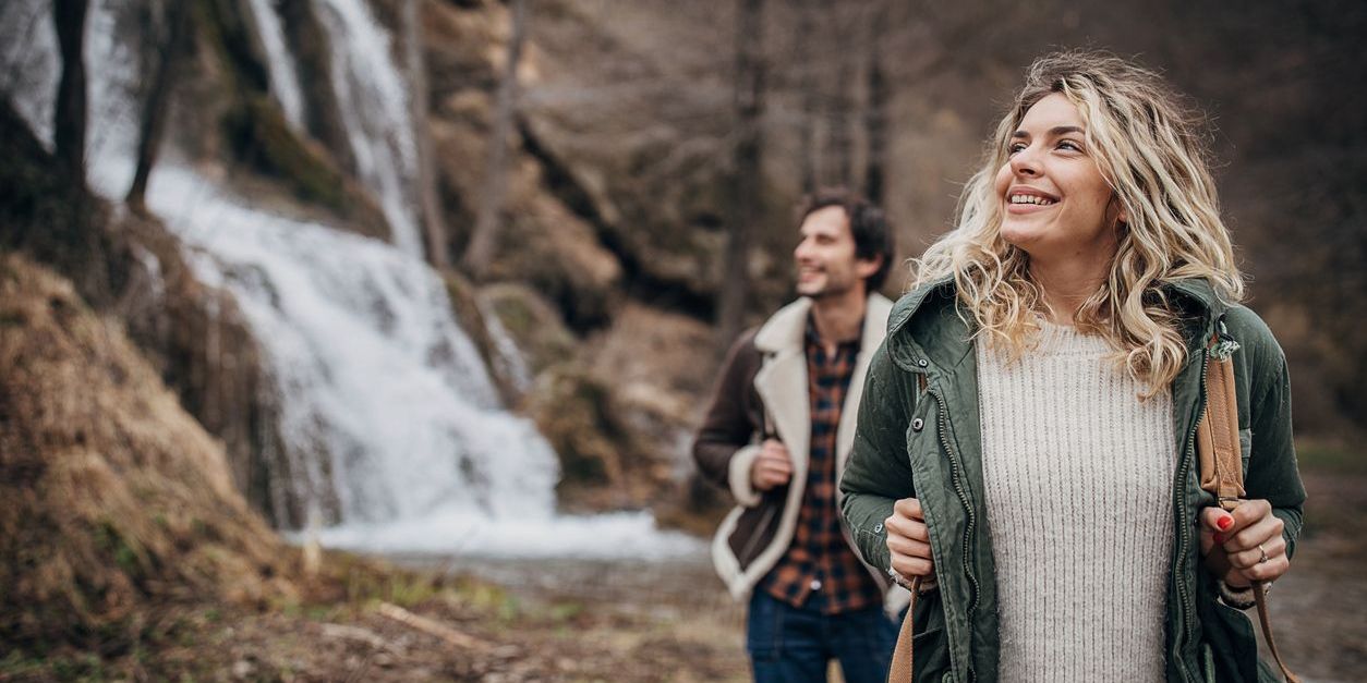 Man and woman, beautiful young couple hiking together in nature on a winter day.