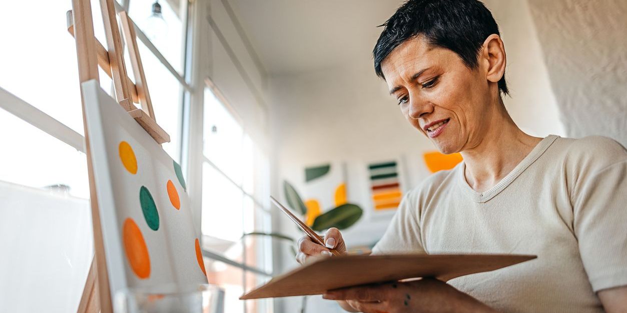 Woman in a light-filled studio paints a canvas.
