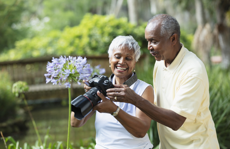 Senior African American couple outside looking at photos taken on a digital camera