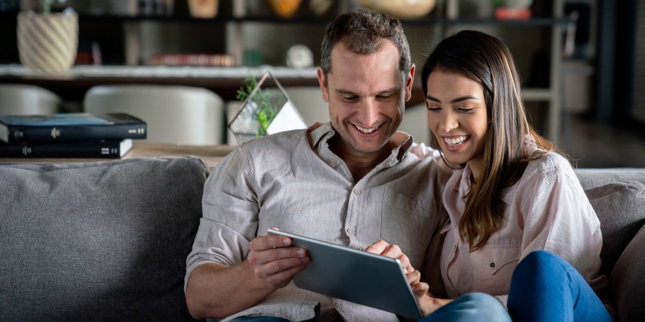 Couple at home looking at investments on their tablet